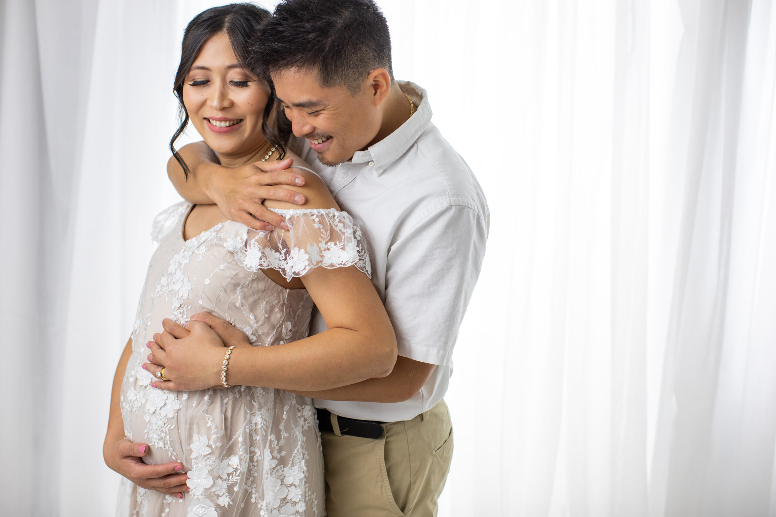 Pregnany couple embracing on a back lit white background in Sparks Nevada portrait studio