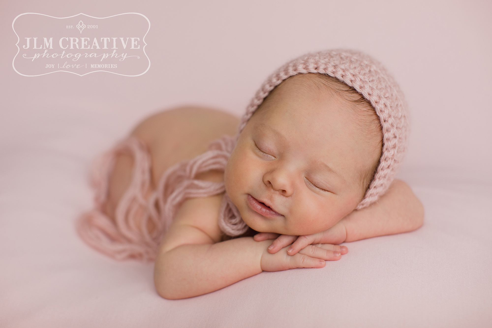 smiling newborn baby girl on pink